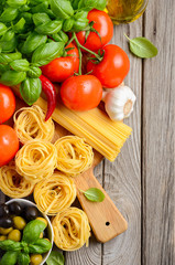 Pasta, vegetables, herbs and spices for Italian food on wooden background, top view