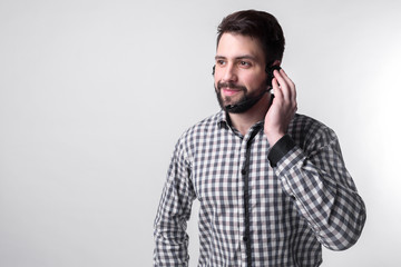 Assistance by telephone. The employee call center helps its customers over the phone. Bearded man isolated on white background.