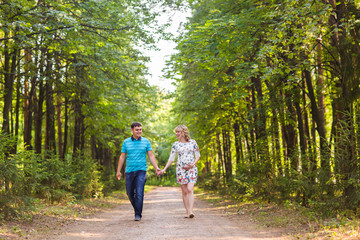 happy young pregnant woman with her husband walking in a park