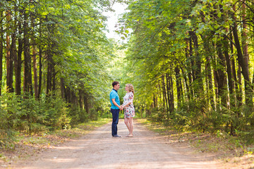 happy young pregnant woman with her husband walking in a park