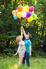 young couple man and his pregnant wife with balloons outdoors