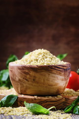 Raw barley bulgur in a wooden bowl, vintage background, selective focus