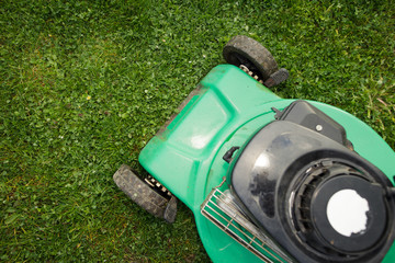 Green mower on the fresh spring grass, ready for cutting