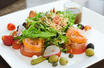Fresh Salmon Salad with vegetables, pomegranate and strawberry