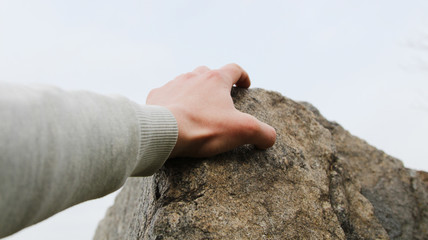 Rock climber's hand grasping handhold on cliff. Depth of field