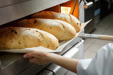 Baker gets hot bread out of the oven