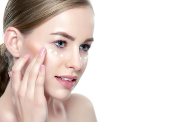 Beautiful Young Blond Woman applying Face cream under her eyes. Facial treatment. Cosmetology,...