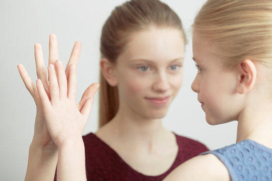 Portrait of two sisters, face to face, touching hands