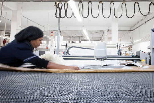 Female factory worker preparing textile for machinery in clothing factory