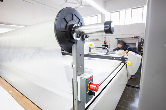 Female factory worker working on pattern cutting machine in clothing factory