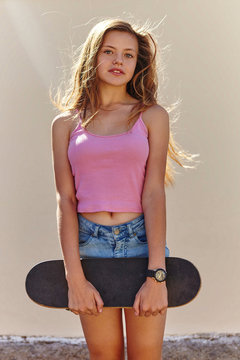 Portrait of teenage girl, outdoors, holding skateboard