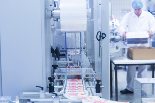 Workers packaging pharmaceutical products on production line in pharmaceutical plant