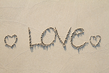 Drawing two hearts on the sand beach with soft shadow, love concept