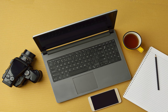 High resolution image of laptop,camera,smart phone and notepad with pencil and coffee on brown background,