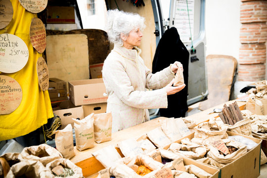 Mature female stall holder selling dried foods at local french market