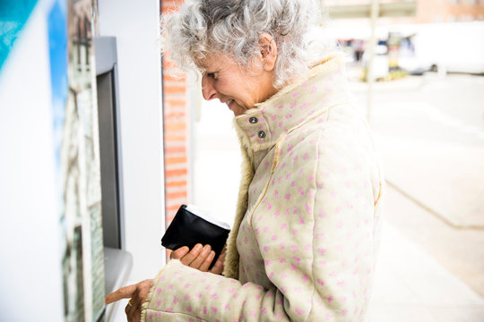Mature woman pressing PIN at local french cash machine
