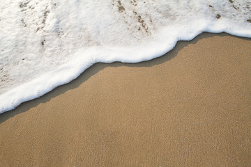 Fototapeta na wymiar Soft wave with bubbles on sandy beach