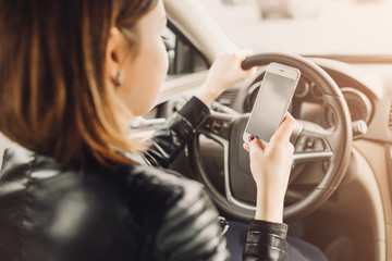 Business woman sitting in car and using her smartphone. Mockup image with female driver and phone screen