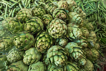 Fototapeta na wymiar A big stack of fresh green delicious artichokes and green beans for them
