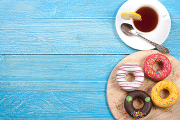 glazed donuts with a cup of tea on a blue wooden background with copy space for your text. Top view