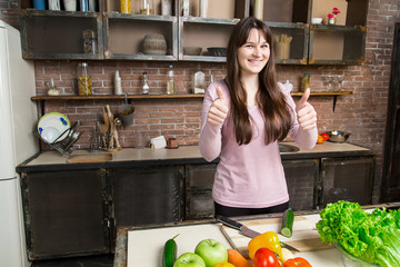 A woman cuts a cucumber in the kitchen with a knife. Preparation of salad and healthy food.