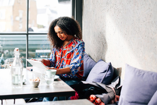 Mid adult woman using digital tablet in cafe