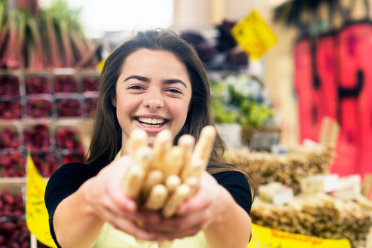 Portrait of young female stall trader holding bunch of breadsticks