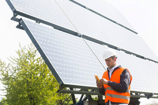 Male engineer using multimeter on solar panel site
