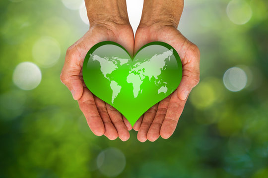 Man's hands holding green heart with world map on blurred green bokeh background, environment concept