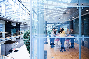 Window view of businesswomen and men having discussion in conference room