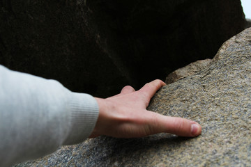Rock climber's hand grasping handhold on cliff. Depth of field