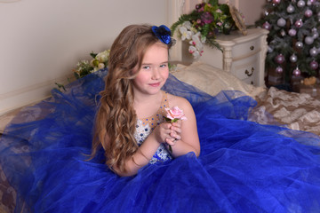 Young princess in a blue evening dress with roses and a little blue hat