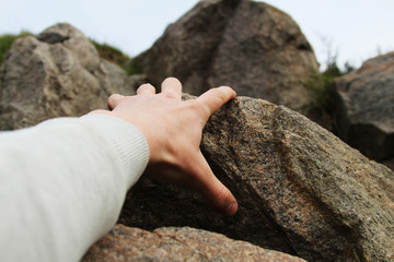 Rock climber's hand grasping handhold on cliff. Depth of field