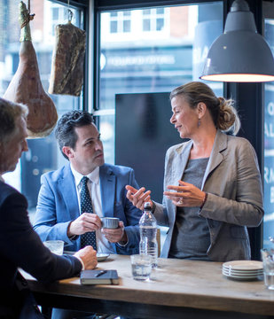 Businessmen and woman having work lunch meeting in restaurant