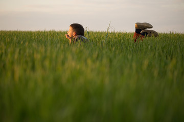 The teenager lies in the tall grass at sunset