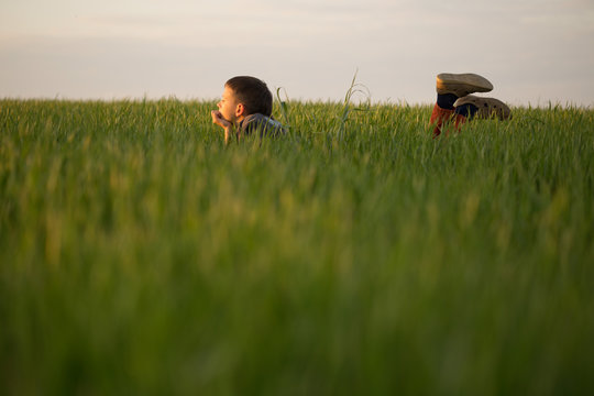 The teenager lies in the tall grass at sunset