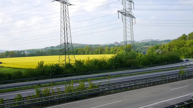 Autobahn mit Rapsfeld und Strommasten