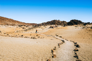 Hiker with a backpack  travels through volcanic landscapes trail of the Canary Islands, Spain