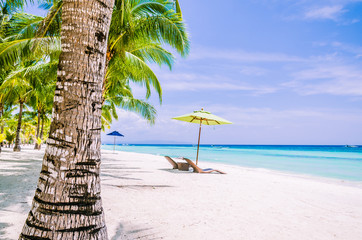 Tropisch strand achtergrond op Panglao Bohol eiland met strandstoelen op het witte zandstrand met blauwe lucht en palmbomen. Reis vakantie