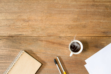 Coffee cup,notebook, white paper and pens on vintage grunge wooden desk,daily business concept
