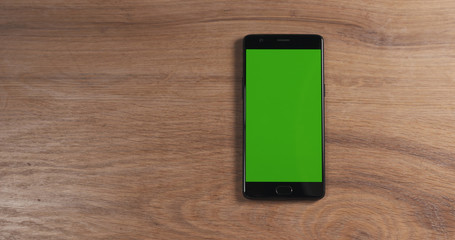 smartphone with green screen over wood table, 4k photo