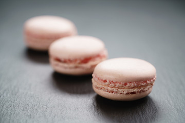 Obraz na płótnie Canvas light pink macarons on slate background, shallow focus