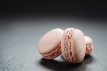 light pink macarons on slate background with copy space, shallow focus