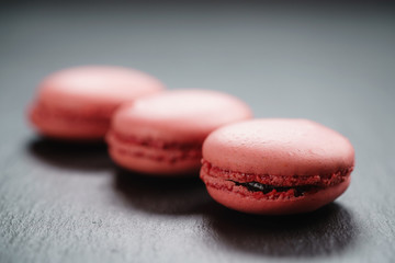 Obraz na płótnie Canvas bright pink macarons on slate background, shallow focus