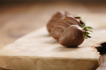 chocolate covered strawberries on wood board, shallow focus