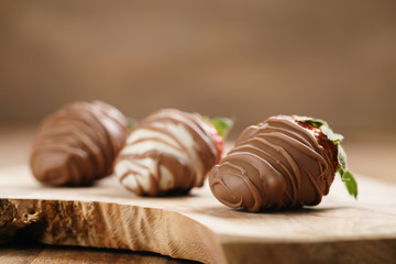 chocolate covered strawberries on wood board, shallow focus