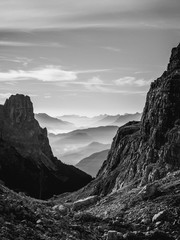 Black and white landscape view of hazy rolling mountains and hills in the Italian Dolomites at sunrise. Portrait orientation.