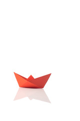 Orange paper ship on white with reflection