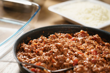 preparing lasagna process with bolognese sauce in pan, shallow focus