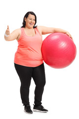 Overweight woman holding pilates ball and making thumb up sign